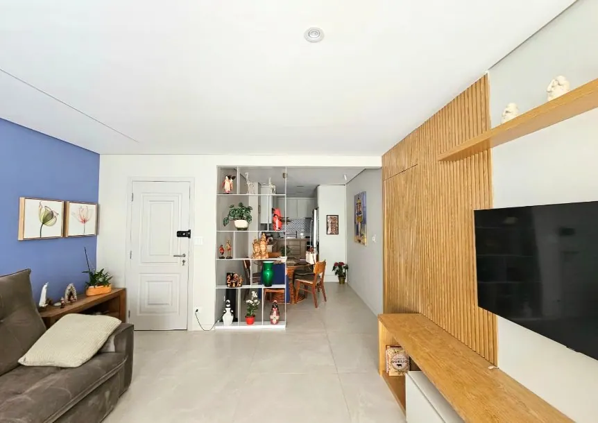 Living com parede azul e painel de madeira em apartamento reformado