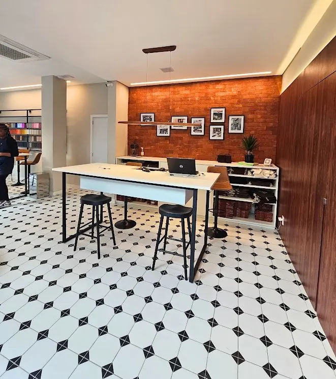 Ateliê com parede de tijolinho e piso geométrico preto e branco