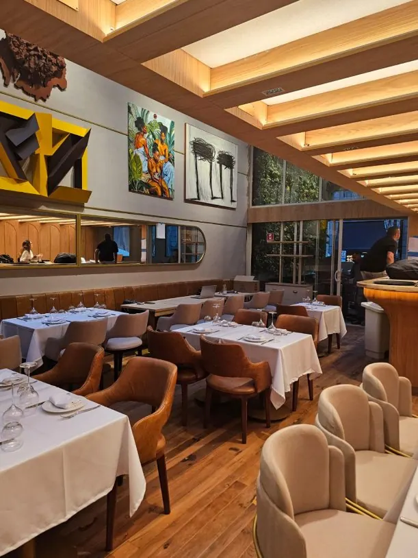 Salão de restaurante com iluminação quente, sancas e mesas postas em São Paulo