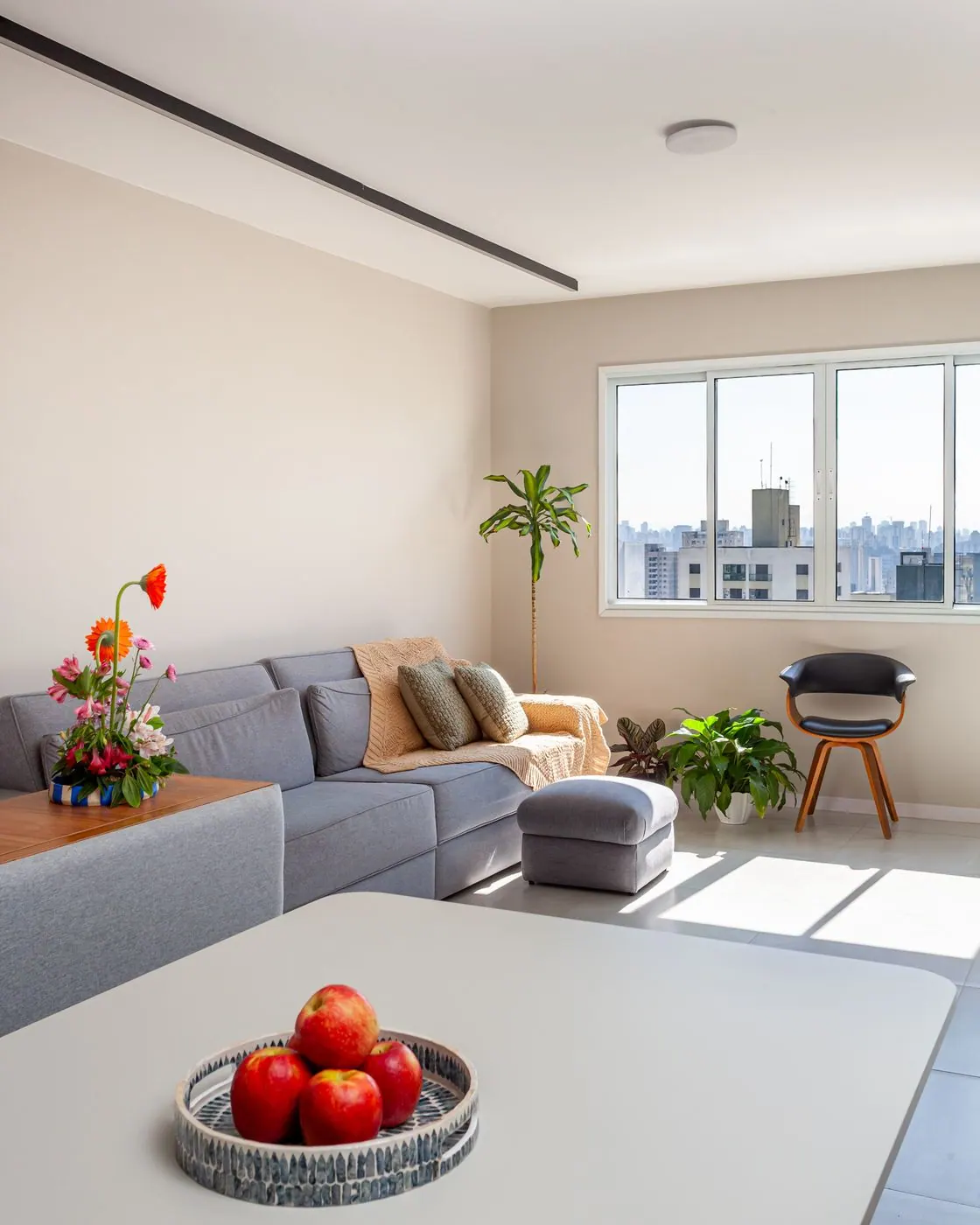 Sala de estar integrada com sofá cinza e muita luz natural