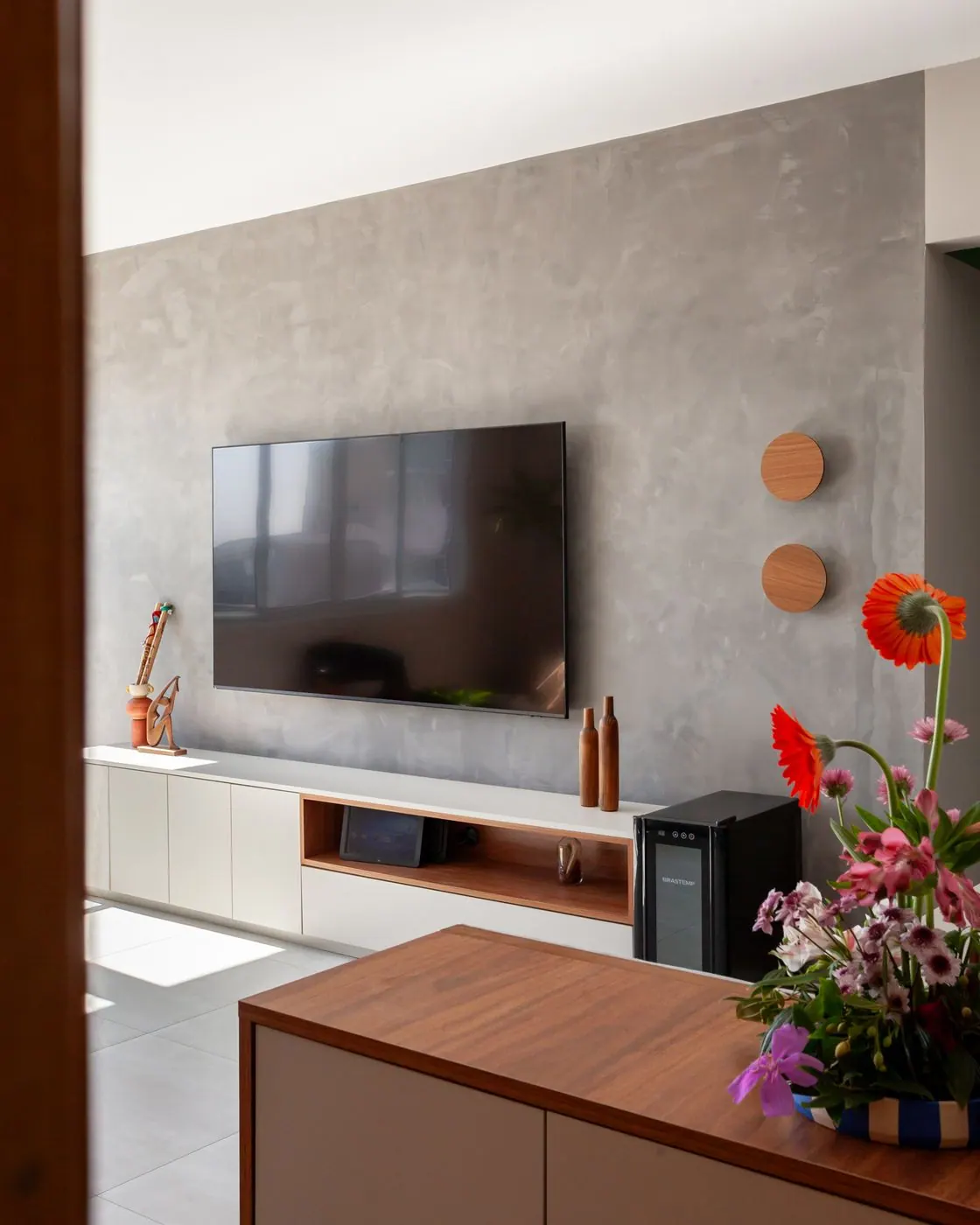 Living integrado com painel de cimento queimado e rack de madeira