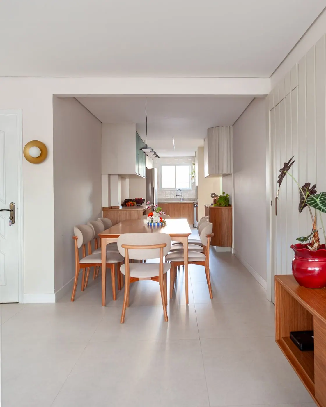 Sala de jantar com painel ripado branco e mesa de madeira após reforma de apartamento em São Paulo