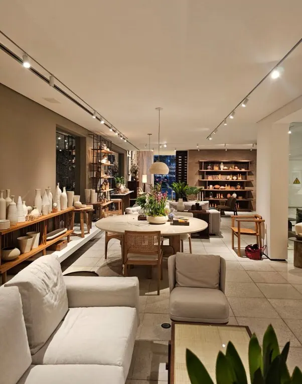 Ambiente de estar em showroom com iluminação quente e destaque para os móveis
