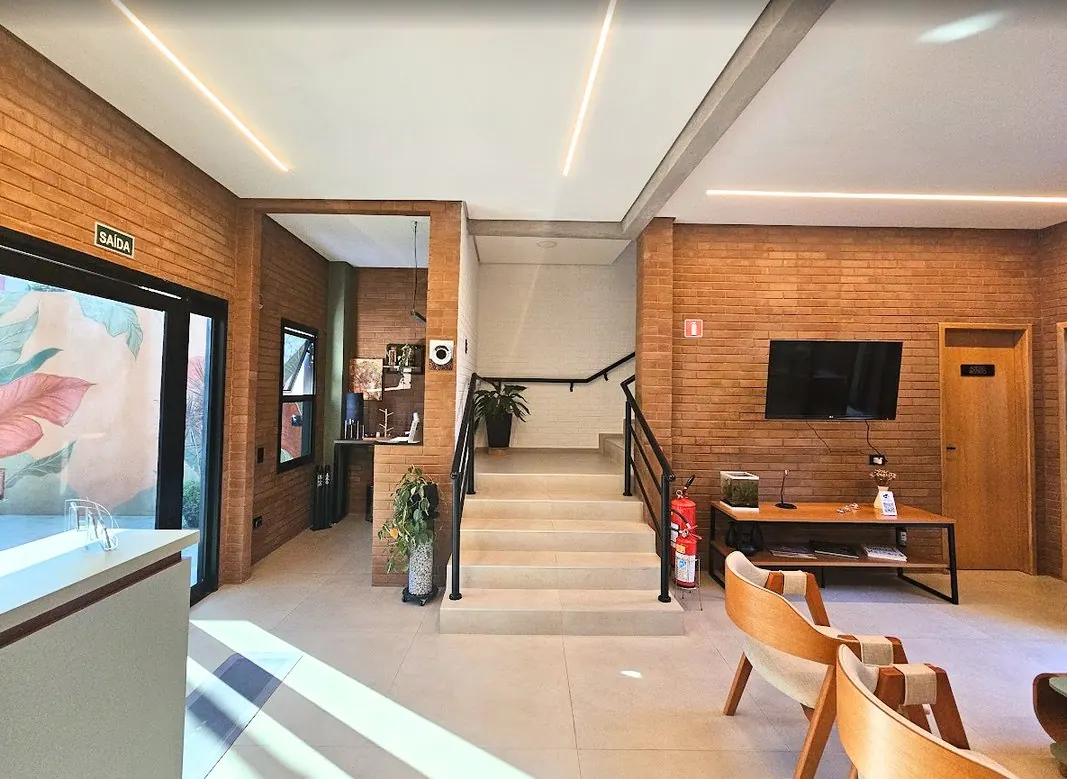 Recepção da clínica com escada metálica e iluminação embutida no forro