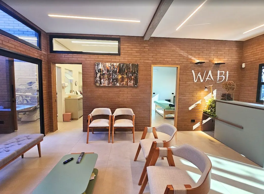 Sala de espera com cadeiras de madeira e iluminação linear em clínica